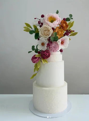 Wedding cake à trois étages blanc orné de fleurs en sucre colorées — pâtisserie de mariage sur mesure à Deauville