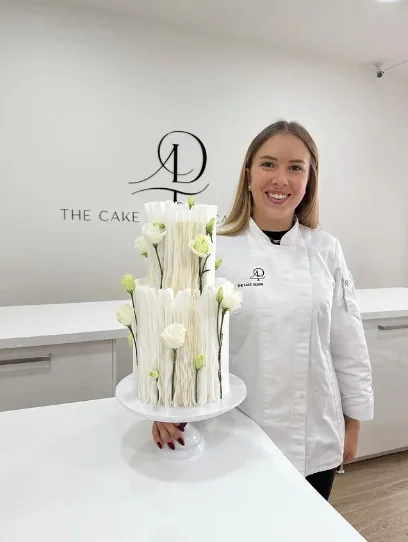 Mélanie, pâtissière passionnée et créatrice de Poppy's Cakes, posant à côté d'un de ses layer cakes à Deauville